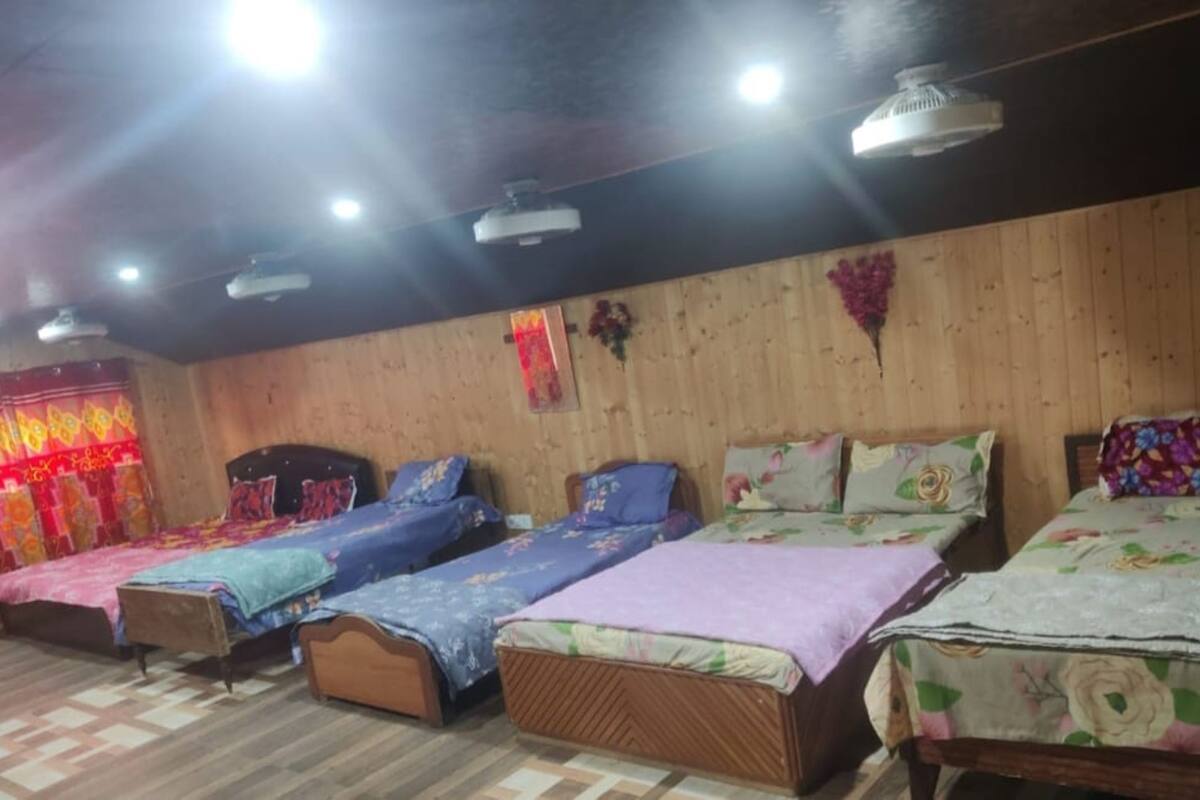 Une chambre avec quatre lits simples, des murs en bois et des ventilateurs de plafond.