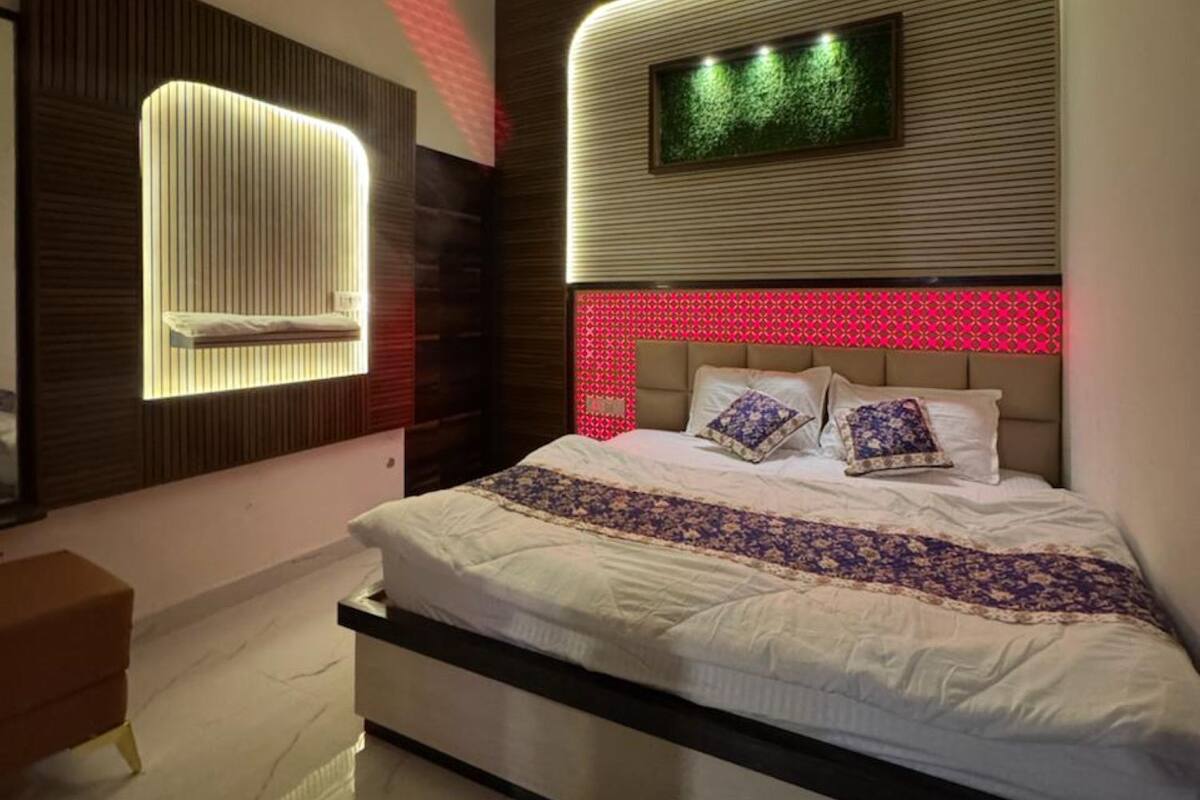 Une chambre moderne dotée d’un grand lit, d’un ventilateur de plafond, d’un téléviseur fixé au mur et d’un système d’éclairage original.