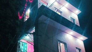 A modern two-story building with large windows and a balcony, illuminated by colorful lights. - Sanwariya Guest House And Resort (Danta Ramgarh)