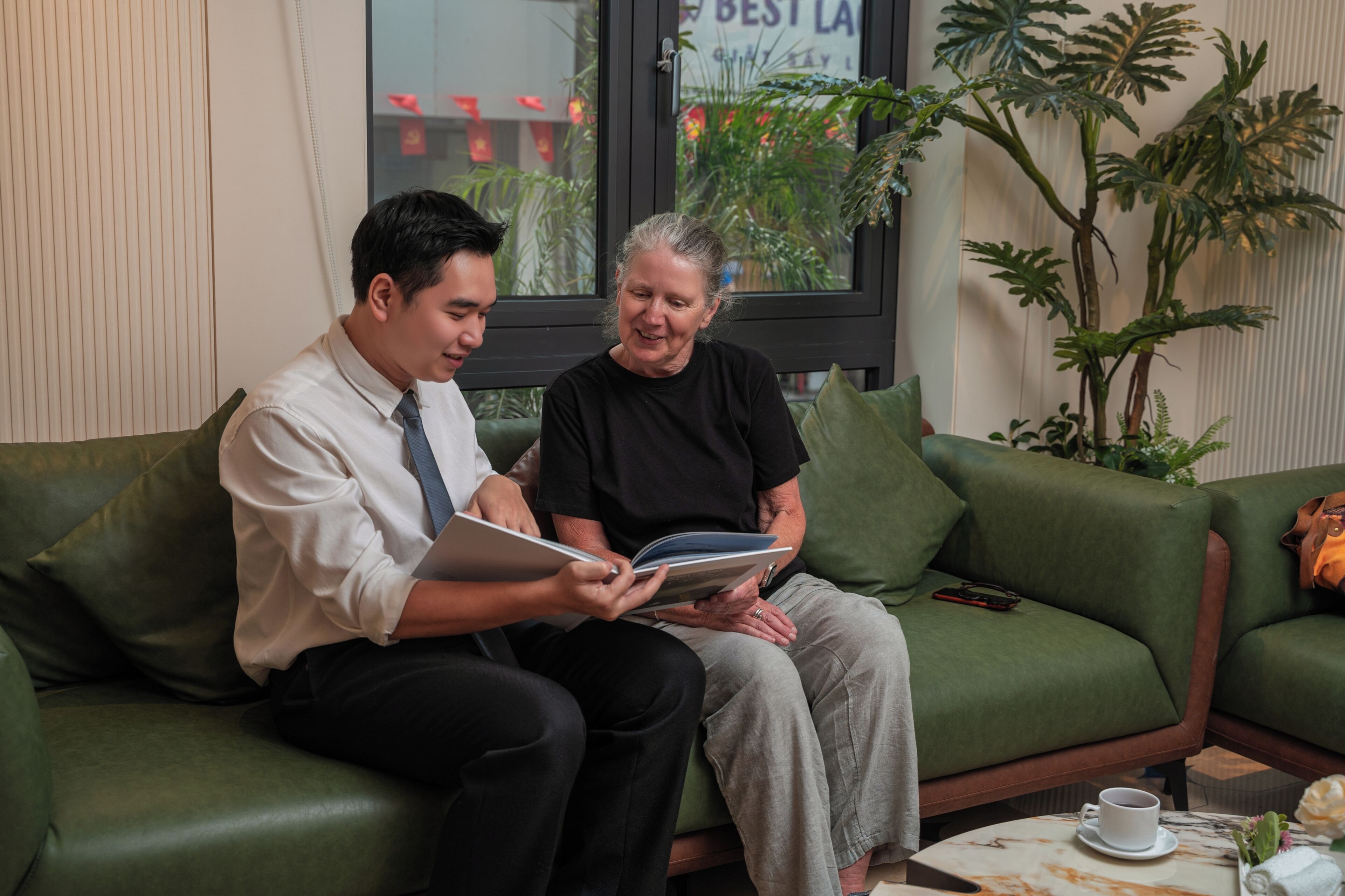Two people sitting on a green sofa, reading a book.