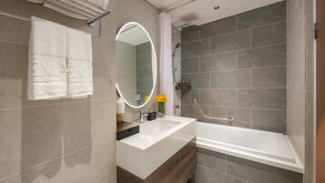 A modern bathroom with a large mirror, a white sink, and a bathtub.