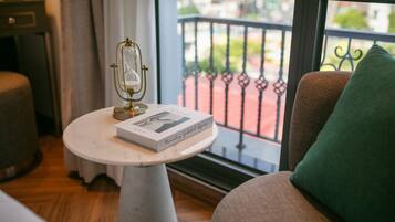 Ein Zimmer mit einem runden weißen Tisch, einem Buch mit dem Titel 'Memories of a German Girl' und einem grünen Kissen auf einem braunen Stuhl.