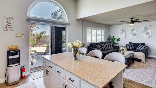 A spacious living area with a kitchen island, a dining table, and a seating area with a couch and chairs. There is a water dispenser and a fire extinguisher visible.