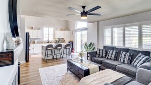 A spacious living room with a gray sofa, a coffee table, and a ceiling fan.