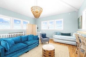 A room with a blue sofa, a grey armchair, a bed, and a wooden coffee table. - Private Pool & Hot Tub, 360° Porch, Steps to Beach (Port St Joe)