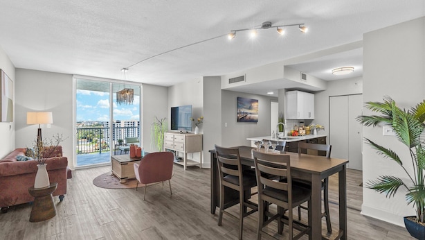 Eine moderne Wohnung mit Essbereich, Küche und einem Balkon mit Blick auf die Stadt.