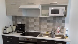 A compact kitchen with a microwave, toaster, coffee maker, and a sink. - Charming house in Tápiószentmárton (Tápiószentmárton)