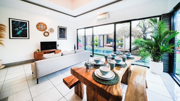 A modern living room with a dining area, a TV, and a pool view.