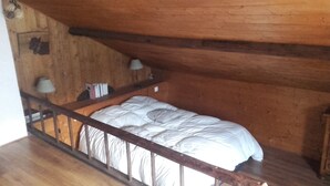 Un lit simple dans une pièce en bois avec un plafond en pente.