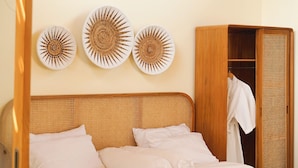 A bedroom with a wooden bed, a wardrobe, and three wall-mounted decorative plates. - Lavillas Jogja (Sleman)