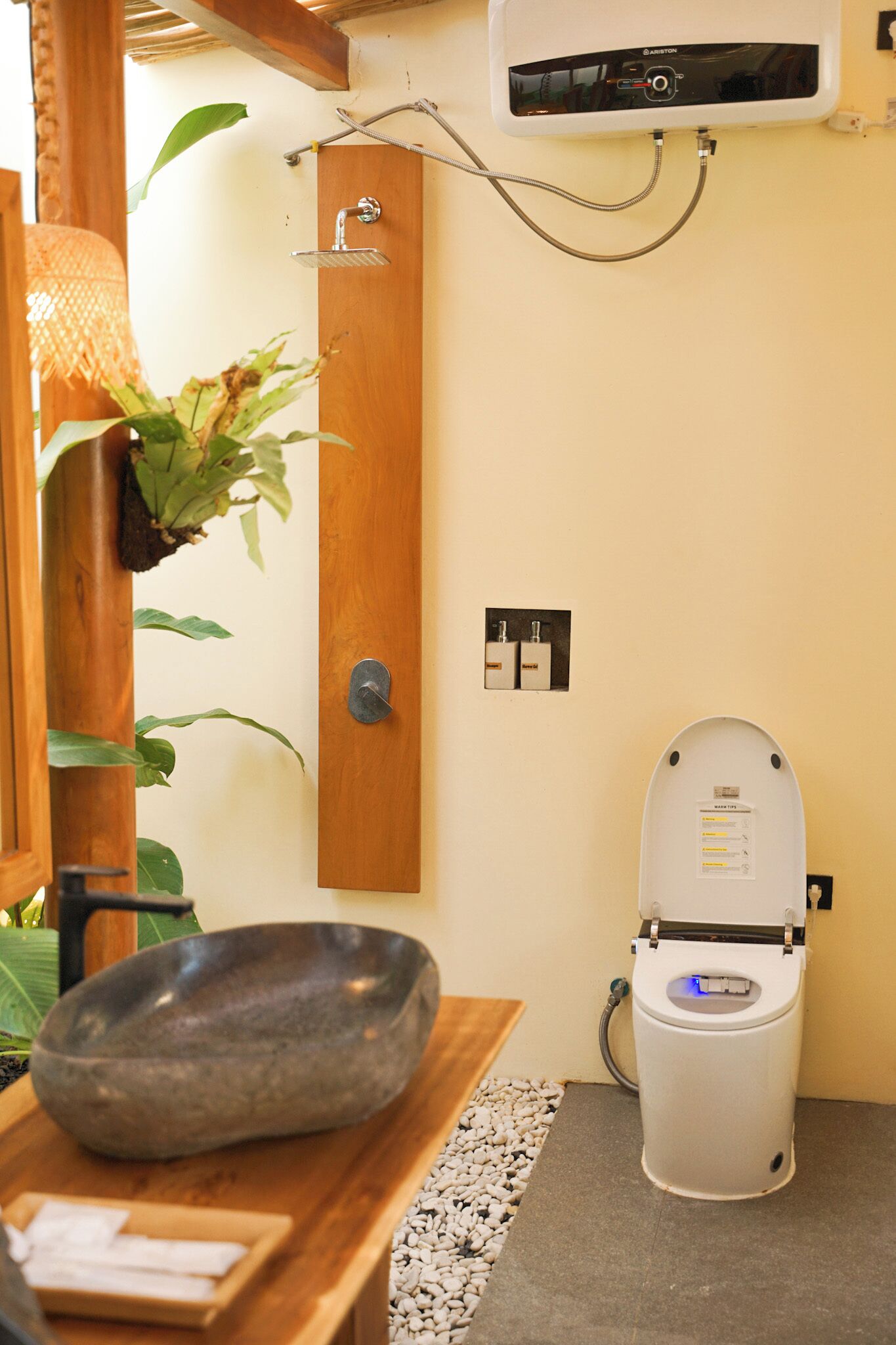 A bathroom with a stone basin, a toilet, a shower, and a wall-mounted air conditioning unit.