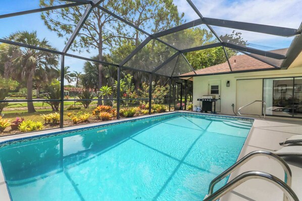 A pool with a glass enclosure, surrounded by tropical plants and trees. - High Tide - 3 Br Sleeps 6 - Private Pool - Games (Naples)