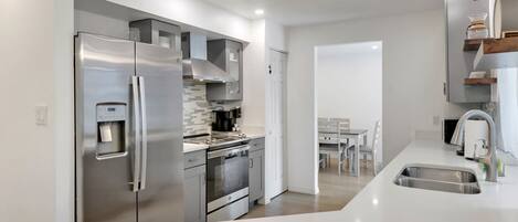 A modern kitchen with stainless steel appliances, a built-in oven, and a water dispenser.