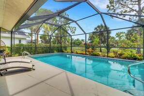 A covered outdoor swimming pool with a clear view of the surrounding greenery and a house in the background. - High Tide - 3 Br Sleeps 6 - Private Pool - Games (Naples)