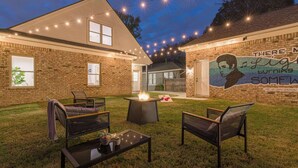 A backyard with a fire pit, outdoor seating, and a mural on the wall.