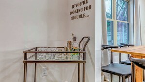 A modern kitchen with a metal cart holding kitchenware, a window with curtains, and a wall with a motivational quote.