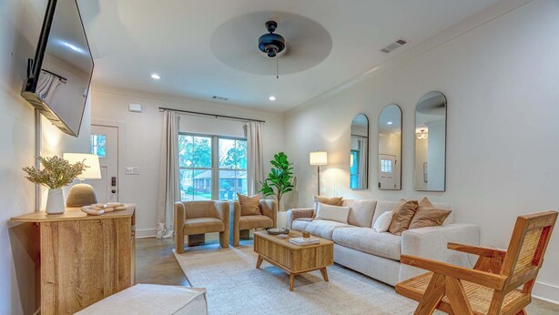 A modern living room with a sofa, chairs, a coffee table, and a wooden side table.