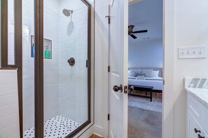 A modern bathroom with a glass shower enclosure, white tiled walls, and a visible bottle of shampoo. - TOP Memphis BnB! The Soul House | Near Beale St (Memphis)