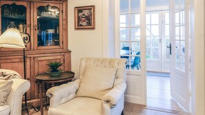 A cozy living room with a beige armchair, a wooden cabinet, and a table with a lamp. - 4 Star Holiday Home in Humlebaek (Humlebaek)