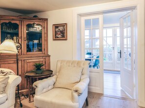 A room with a beige armchair, a wooden cabinet, and a table with a lamp. - 4 Star Holiday Home in Humlebaek (Humlebaek)