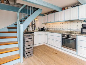 A kitchen with white cabinets, a wooden staircase, and a tiled backsplash. - 4 Star Holiday Home in Humlebaek (Humlebaek)