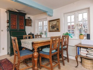 A dining area with a wooden table and chairs, a green cabinet, and a painting on the wall. - 4 Star Holiday Home in Humlebaek (Humlebaek)