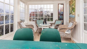 A sunroom with wicker furniture, a table, and a view of the outside. - 4 Star Holiday Home in Humlebaek (Humlebaek)