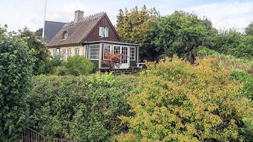 A house with a large garden, a wooden fence, and a thatched roof.