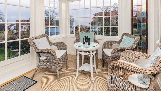 A sunroom with wicker furniture, large windows, and a view of the outside. - 4 Star Holiday Home in Humlebaek (Humlebaek)