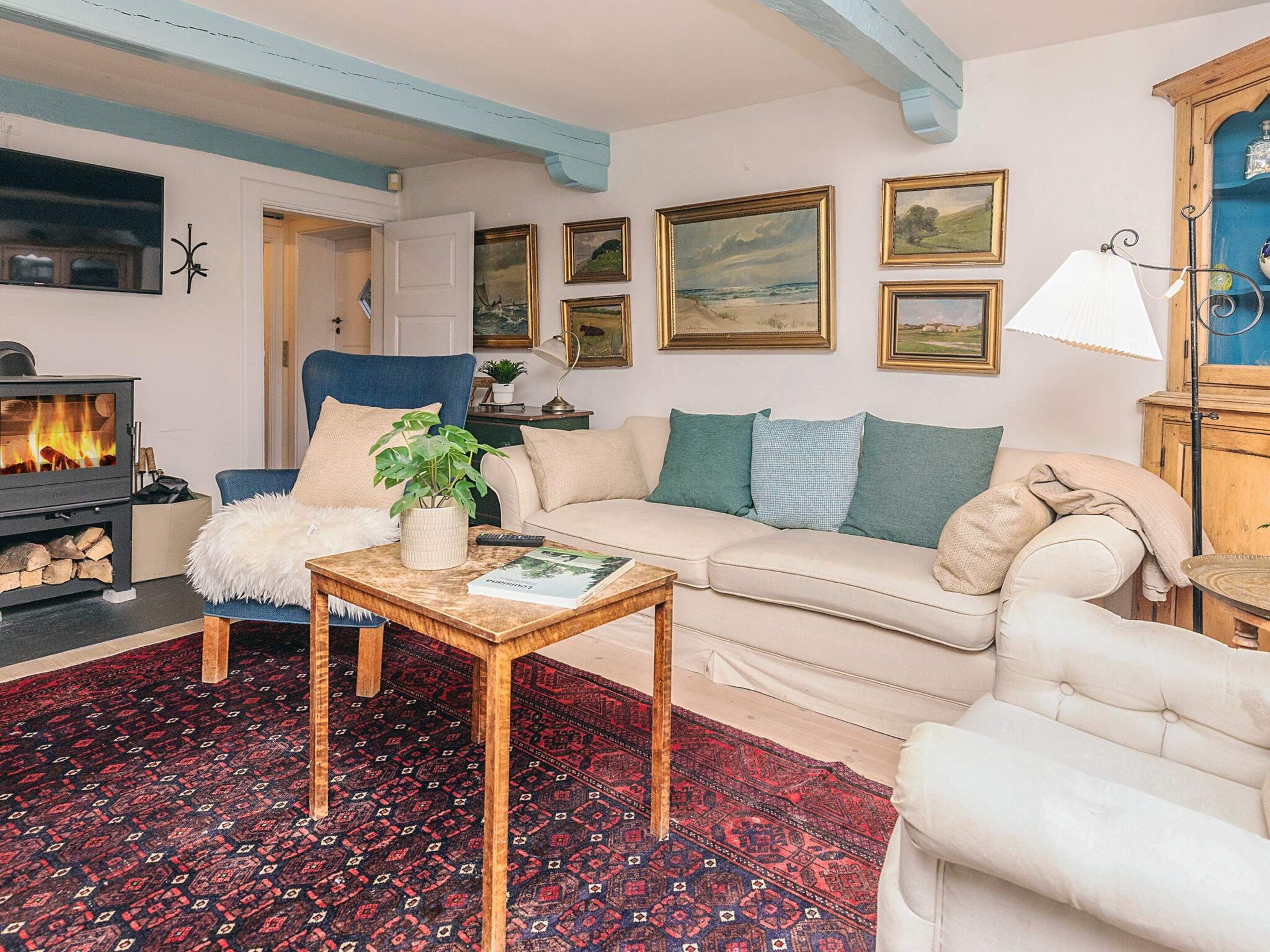 A cozy living room with a fireplace, a sofa, a chair, a coffee table, and a patterned rug.