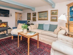 A cozy living room with a fireplace, a sofa, a chair, a coffee table, and a patterned rug. - 4 Star Holiday Home in Humlebaek (Humlebaek)