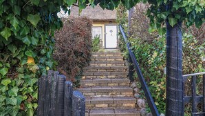 A stone staircase leading to a door with a thatched roof, surrounded by greenery. - 4 Star Holiday Home in Humlebaek (Humlebaek)