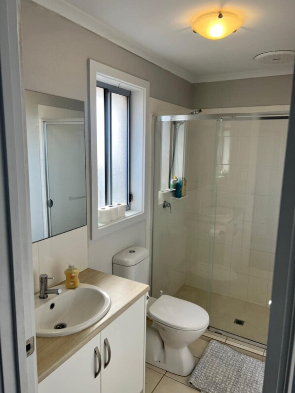 A modern bathroom with a shower, toilet, and sink.