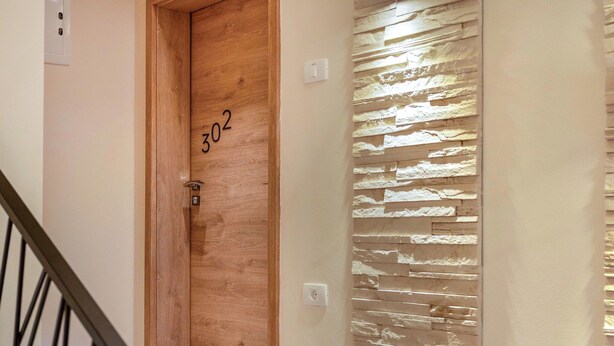 A wooden door with the number 302, a stone-textured wall, and a metal staircase railing. - Adelsberg Inn by Interhome (Postojna)
