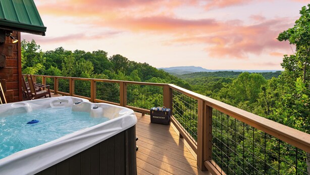A hot tub on a wooden deck with a view of a forested landscape. - Sleeps 22, 2 Homes | Theater Room, Game Room, Hot Tub, Smoky Mountain Views (Sevierville)