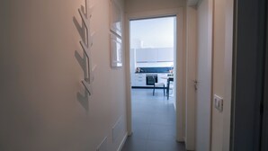 Passatge que condueix a una cuina amb armaris blancs i una zona de menjador.