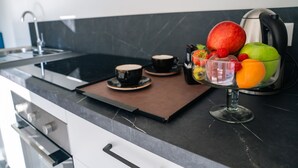 Una cuina moderna amb taulell de marbre, una cafetera i un plat de fruita.