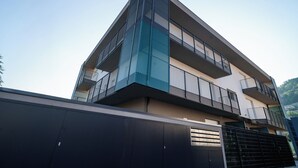 Un edifici modern de diversos pisos amb balcons, un terrat pla i una entrada tancada per reixa.