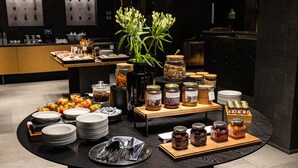 Taula de buffet amb diversos plats, incloent pots de condiments i flors fresques.