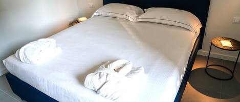A neatly made bed with white linens and two towels on the bed.