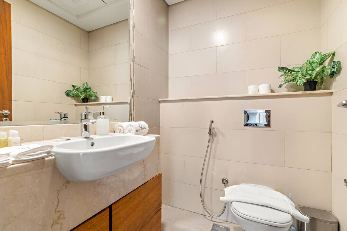 Een moderne badkamer met wastafel, spiegel, handdoekhouder en douche.