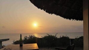 Vista al atardecer desde una terraza con una mesa y una botella, con vista al mar.