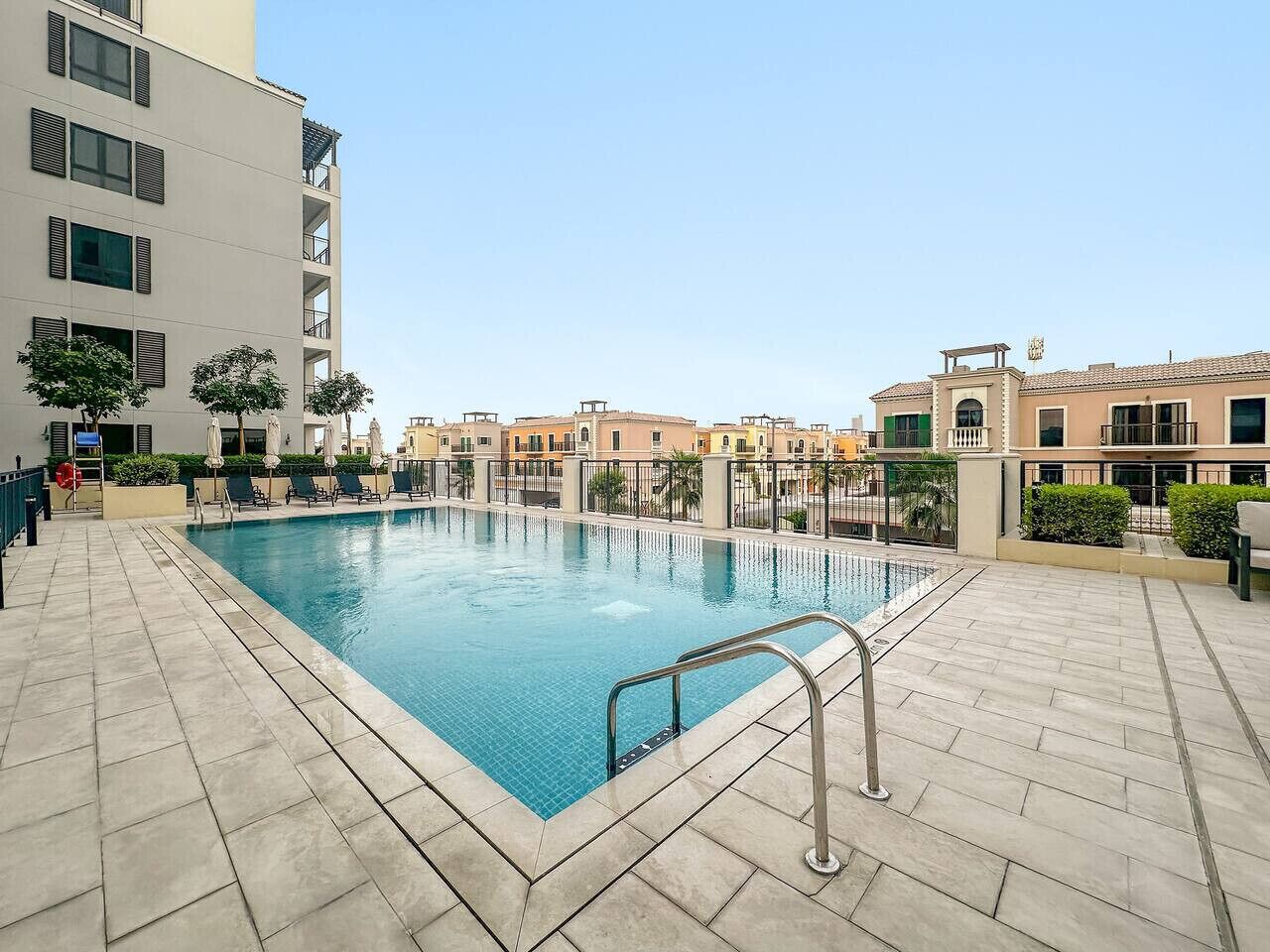 Ein rechteckiger Pool mit Metallleiter, umgeben von einer gefliesten Terrasse.