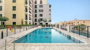 A rectangular swimming pool with a depth marker, surrounded by a tiled deck and a metal railing. - Luxury La Mer 1BR | Balcony Sea Views + Near City Walk & Mall (Dubai)
