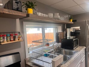 A kitchen with a built-in dishwasher, a coffee maker, and a window with a view of a wooden fence.