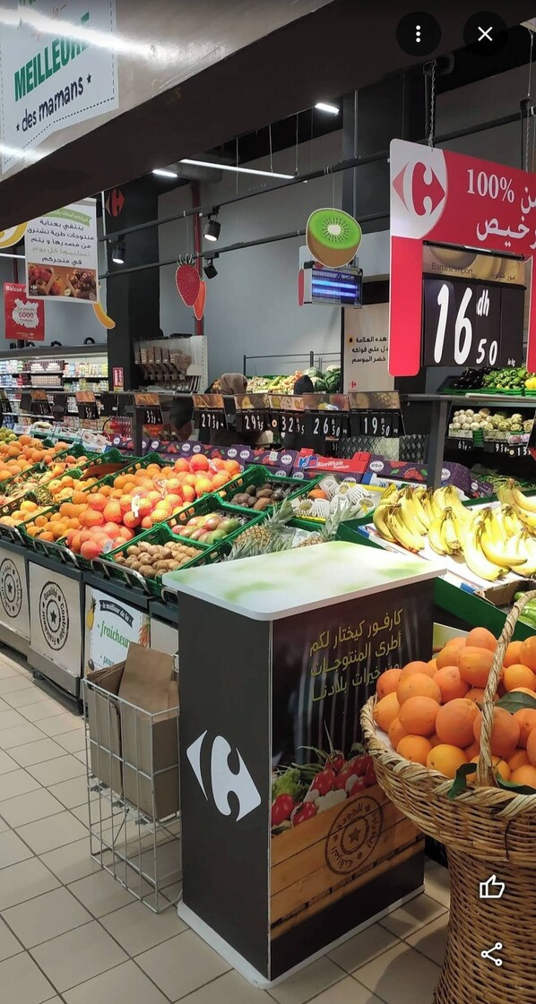 A grocery store with various fruits and vegetables on display, price tags, and promotional signs.