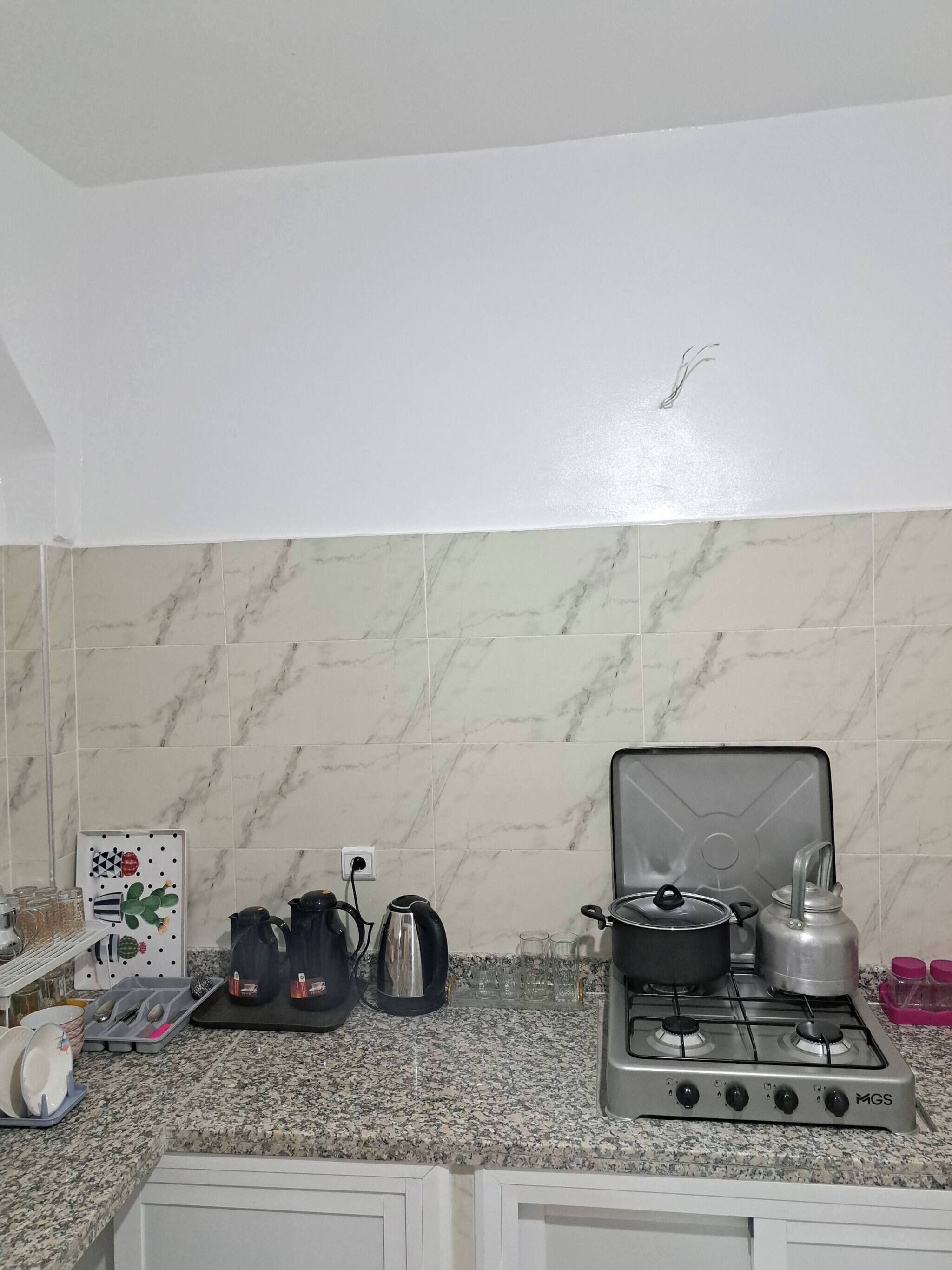 A kitchen with a gas stove, a kettle, a coffee maker, and a microwave.