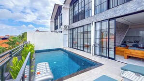 A modern outdoor pool area with a clear view of the cityscape, a lounge chair, and a wooden bench. - Seminyak Loft 360 Bali (Seminyak)