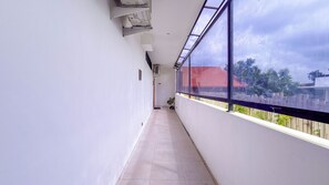 A narrow balcony with a view of a red-roofed building and trees. - Seminyak Loft 360 Bali (Seminyak)