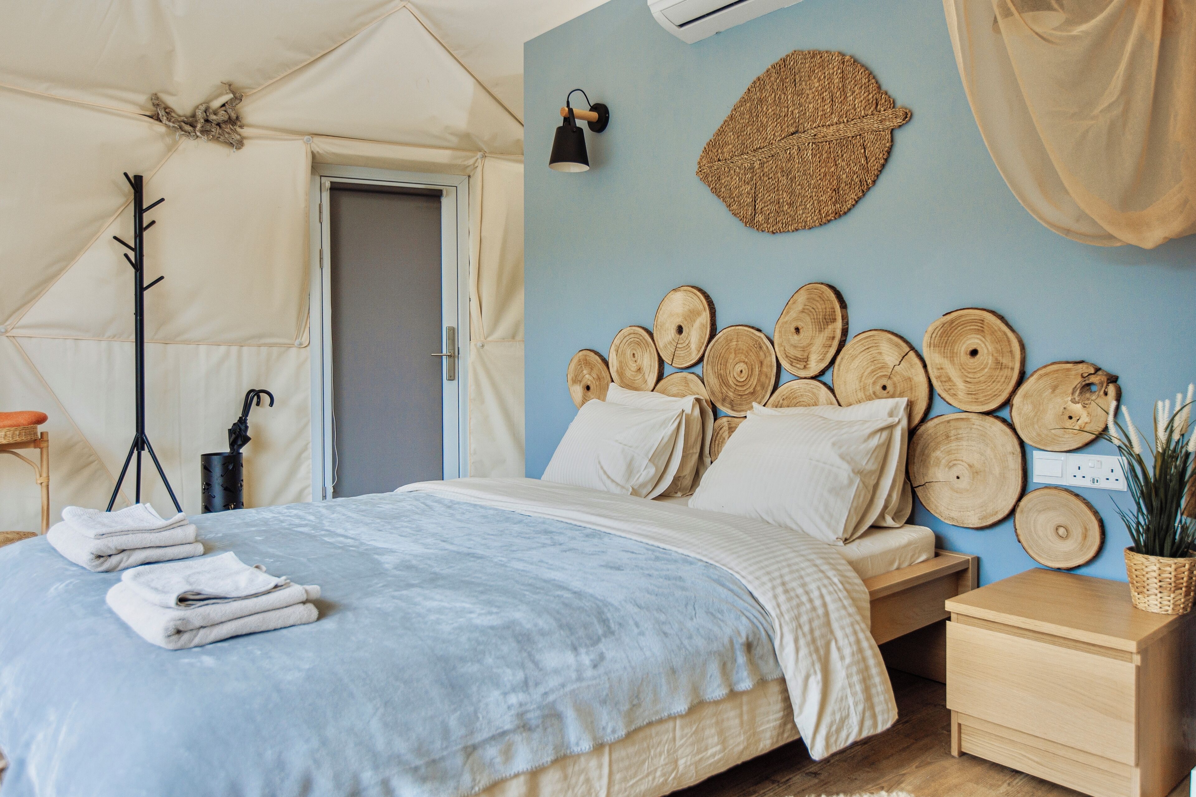 Une chambre à coucher comprenant un lit, des tables de chevet, un luminaire fixé au mur et une porte.